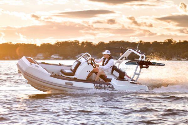 Person driving a small motorboat at sunset.