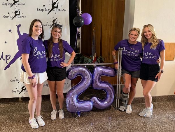 Four women in purple Step Up Dance shirts celebrate 25 years with balloons.