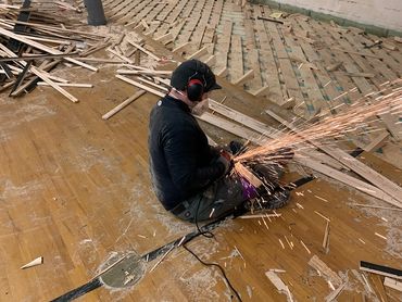Grinding nails off of reclaimed gym floor for reuse in a future tiny home.