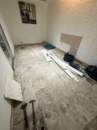 Room under renovation with removed flooring and tools scattered.
