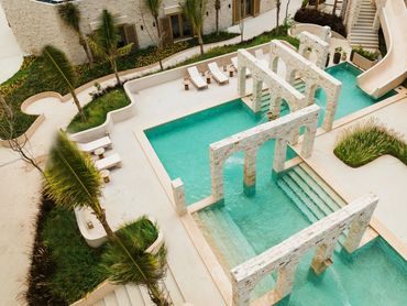 Gorgeous pool at Corasol featuring elegant columns and a thrilling water slide, capturing fun luxury