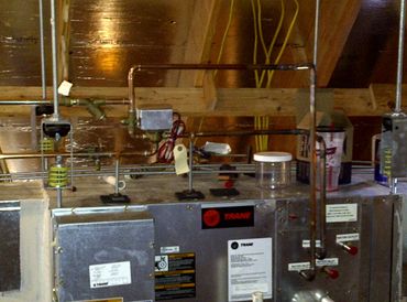 A Trane HVAC system installed in an attic with copper piping and wiring.