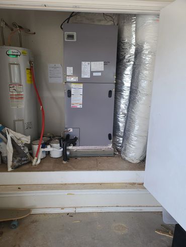 HVAC system and water heater installed in a utility closet with ducts and pipes.