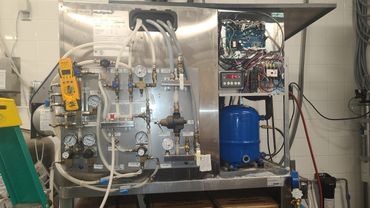 Industrial refrigeration equipment with gauges, pipes, and control panel.