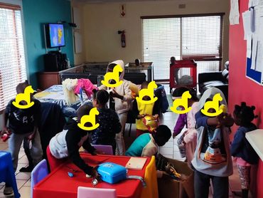 Children playing and interacting in a colorful indoor classroom setting.