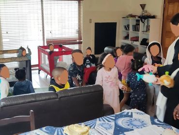 A group of children and adults interacting in a living room.