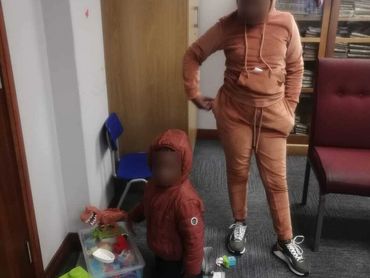 Two children in hoodies playing with toys in a room.