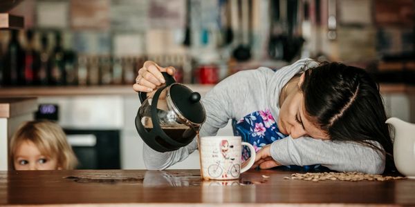 lady sleeping on table while pouring coffee while child looks on