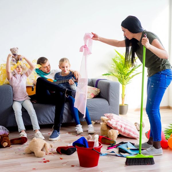 mom showing her husband and kids the stuff she is cleaning off of the floor while they play