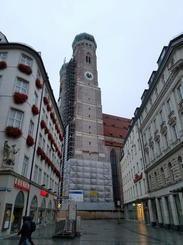 Historic church tower under renovation in a European city street.