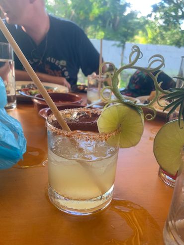 Refreshing cocktail with a spiced rim and lime garnish on a wooden table.