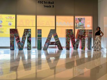 Colorful Miami art installation with a woman posing beside the letters.