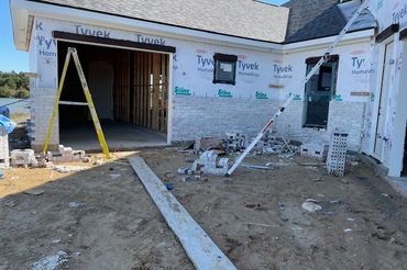 House under construction with bricks and ladders outside.
