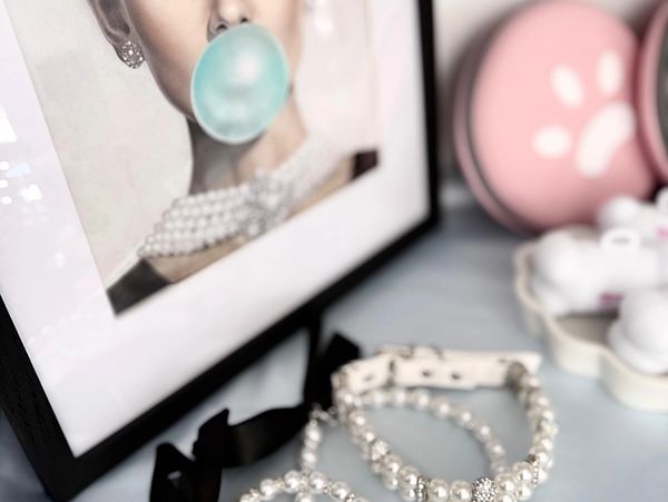 Pearl necklaces displayed near a framed photo of a woman blowing bubblegum.