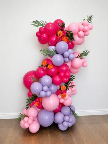 Colorful balloon arrangement with flowers and leaves.