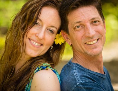Smiling couple outdoors with a yellow flower.
