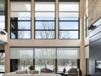 Modern living room with tall windows and neutral furniture.
