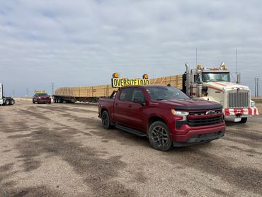 Two trucks with oversized load signs transporting lumber.