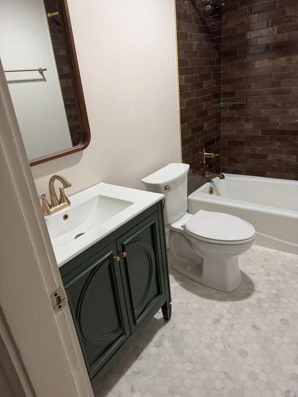 Clean bathroom with dark green vanity and white fixtures.