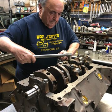 Man working on an engine block in a workshop.