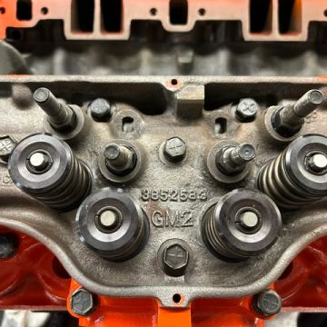 Close-up of an engine cylinder head with springs and bolts.