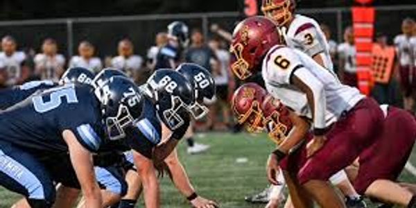 Two football teams lined up facing each other on the field.