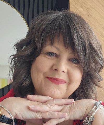 Smiling woman resting chin on crossed hands.