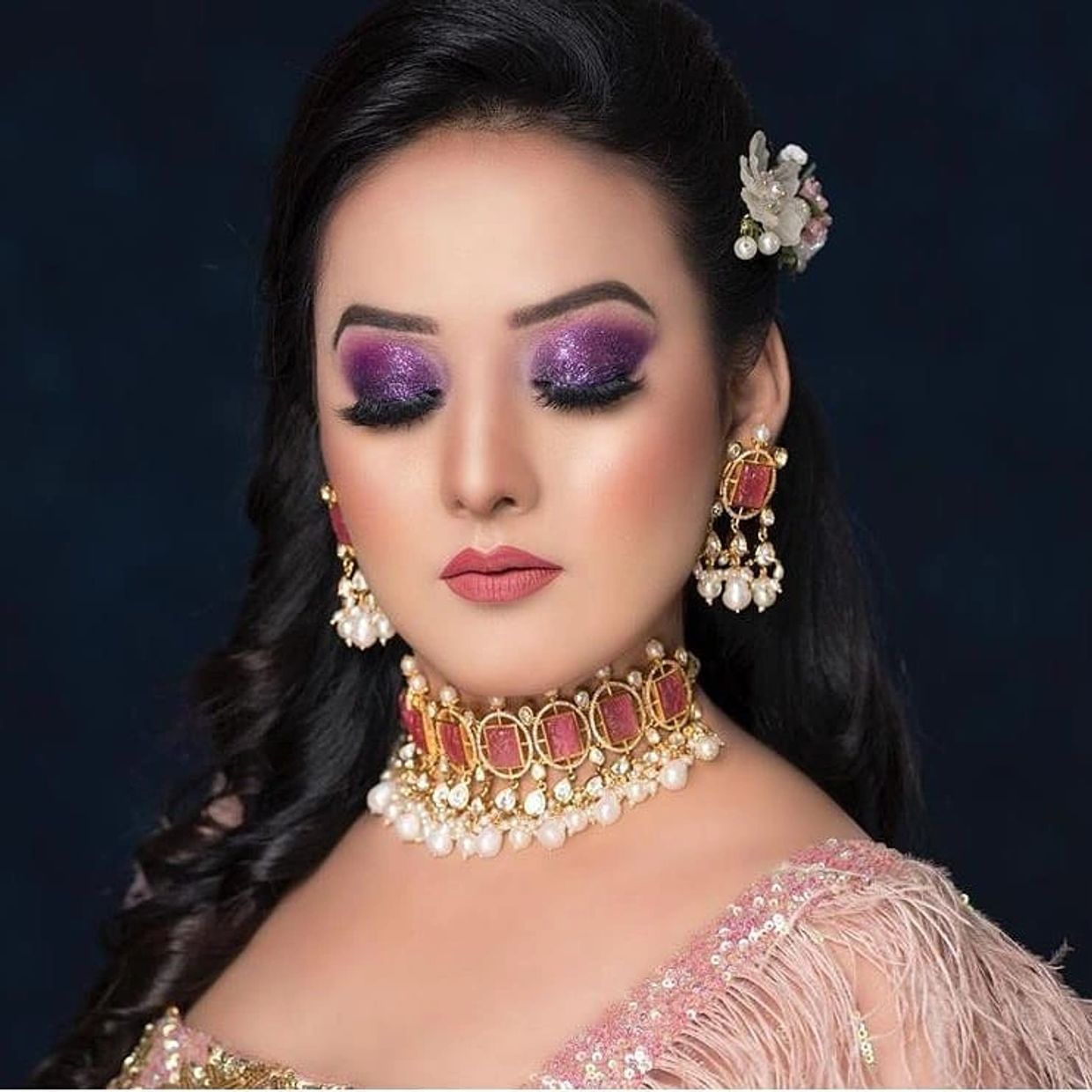 Woman with glittery purple eye makeup and traditional jewelry.