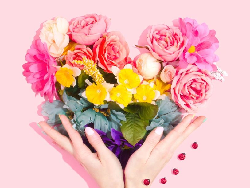 Hands holding a heart-shaped flower bouquet.