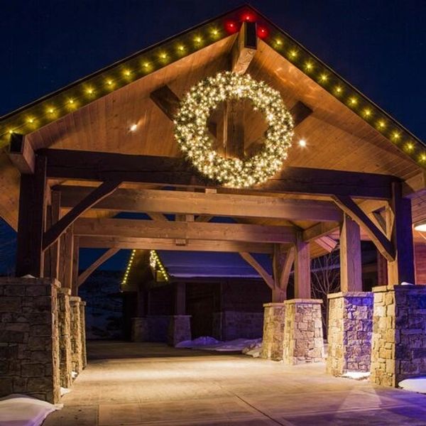 oversized lit wreath on open rustic pavilion rope lights border roof line