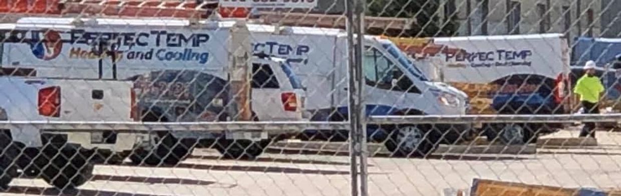Service trucks parked behind a chain-link fence at a worksite.