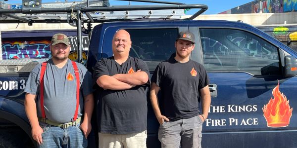 Three men standing in front of a Kings Fire Place van.