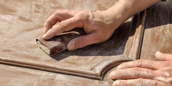 A person sanding a piece of wood