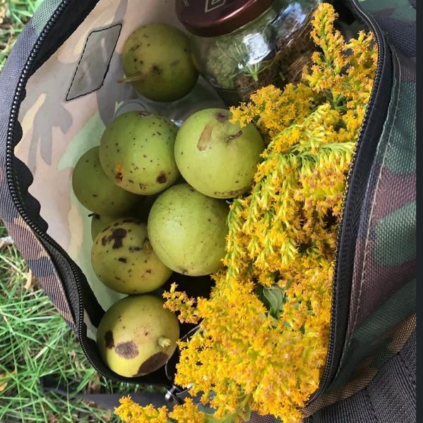 A bag filled with green apples and bright yellow flowers.
