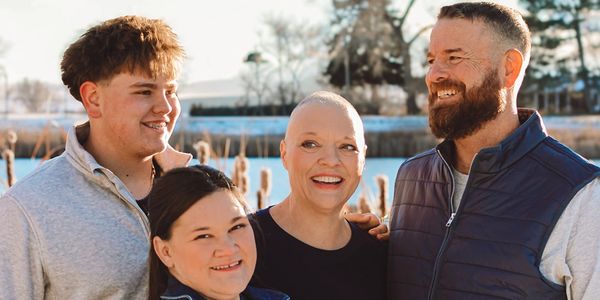 Four smiling people enjoying a sunny outdoor moment together.