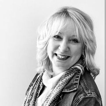 Smiling woman with light hair in a denim jacket against a white background.