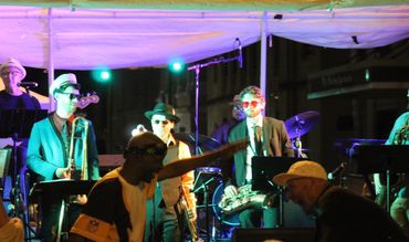 Matt Hill & The Classics performing on a large outdoor stage at a lively festival street party.