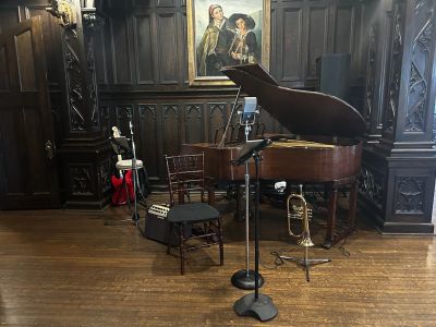 Jazz trio setup with grand piano, flugelhorn and guitar in a wood-paneled room, ready for a celebrat