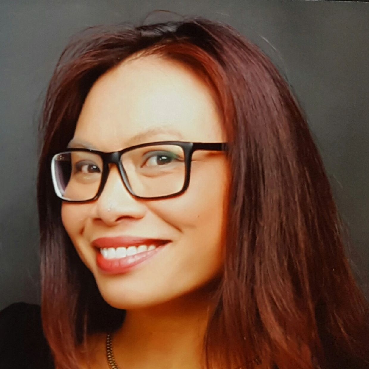 Femme souriante avec des lunettes et des cheveux roux.