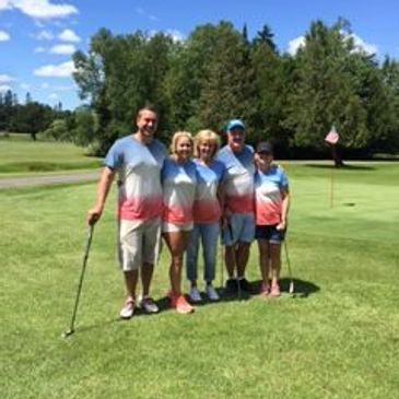 Golf league people smiling and standing in front of a putting green with golf clubs