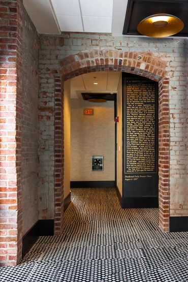 Brick archway leading to a hallway with patterned flooring and an exit sign.
