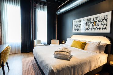 Modern hotel room with a large bed and cozy seating area.