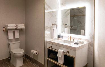 Modern bathroom with marble countertop and illuminated mirror.