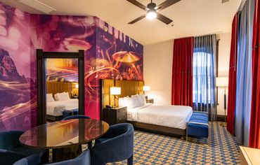 Vibrant hotel room with artistic wall mural and bold decor.