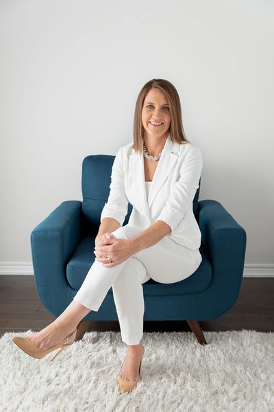 Owner wearing white pant suit sitting on a blue chair
