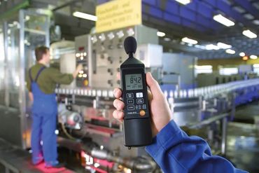 Sound level meter measuring noise in a factory setting.