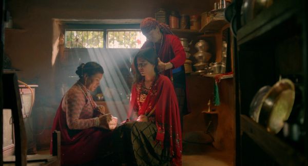 Three women engaged in traditional activities inside a cozy room.