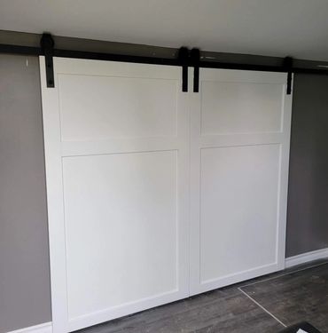 Homemade craftsman style doors painted in white and hung on a barn door hinge.