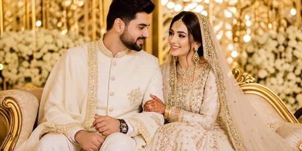 Newlywed couple in traditional attire smiling at each other.