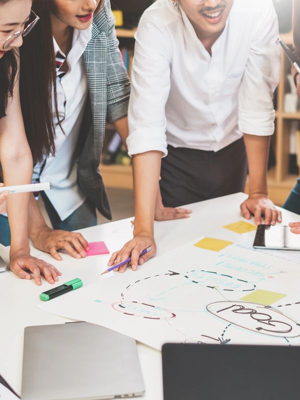 A team of individuals from diverse backgrounds, standing around a table, discussing a project goal
